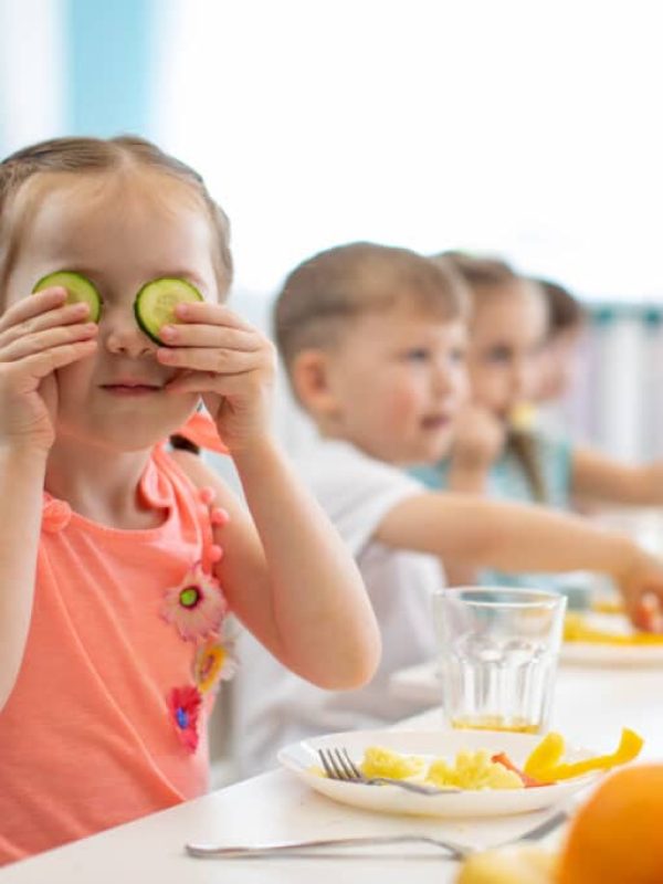 Funny kid eating healthy food in kindergarten or daycare